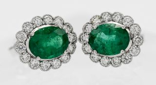 A fine pair of 18ct white gold diamond and emerald cluster earrings, centred oval cut emeralds,