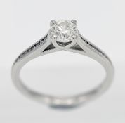 A platinum diamond solitaire ring with channel set shoulders