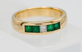 An 18ct yellow gold band channel set ring set with a princess cut diamond and four emeralds, band