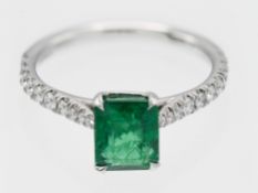 An emerald and diamond single stone ring set in platinum stamped 950, set with diamonds half band,