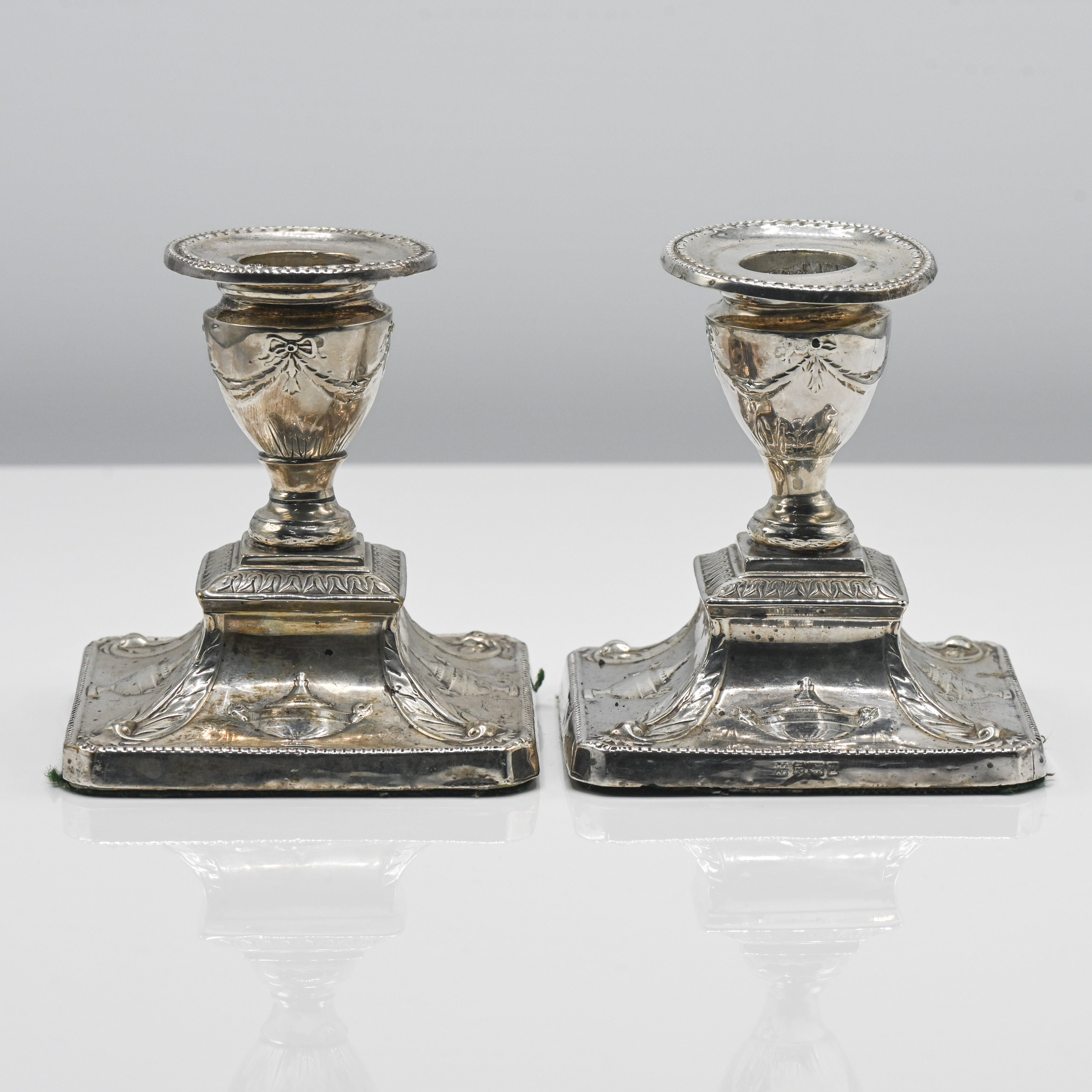 A pair of Edwardian short silver candle holders of Adam design, indistinct hallmarks for