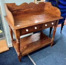 An early 20th century pitch pine wash stand with three quarter gallery, two drawers and lower