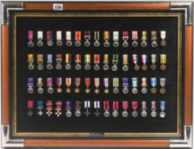 A replica collection of British Campaign and Gallantry miniature medals mounted on a framed board,