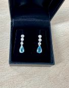 A pair of 18ct white gold three stone diamond and pear shape aquamarine drop earrings