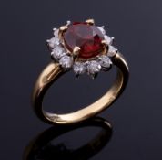 An 18ct yellow gold cluster ring set with a central oval cut orange garnet, approx. 2.50 carats,