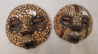 Two African face masks with applied shell decoration, diameter of largest 31cm (2).