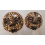 Two African face masks with applied shell decoration, diameter of largest 31cm (2).