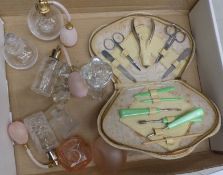 A collection of glass perfume bottles and atomisers together with a vintage cased manicure set.