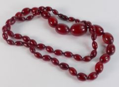 A graduated cherry amber necklace, oblong beads on knotted string strand, the largest bead 3cm wide,