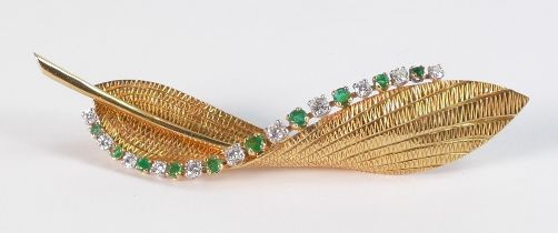 A Garrard & Co 18ct gold twisted single leaf brooch, set along one edge with ten emeralds and eleven