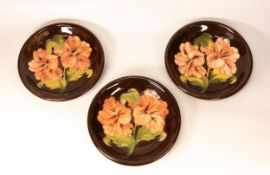 Three Moorcroft Hibiscus on brown shallow bowls. Diameter 21.5cm