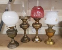 A collection of 4 brass oil lamps all with chimneys (1 is missing glass shade)