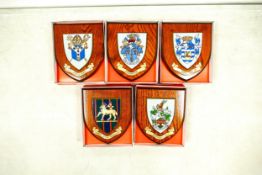 A collection of boxed wooden heraldic shields each with hand painted raised shield, including