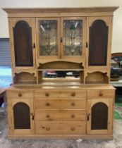 A late victorian large two piece stripped Pine dresser with carved oak panels depicting Diana and