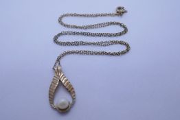 9ct yellow gold drop shaped pendant mounted with a single pearl on an unmarked yellow metal chain, w