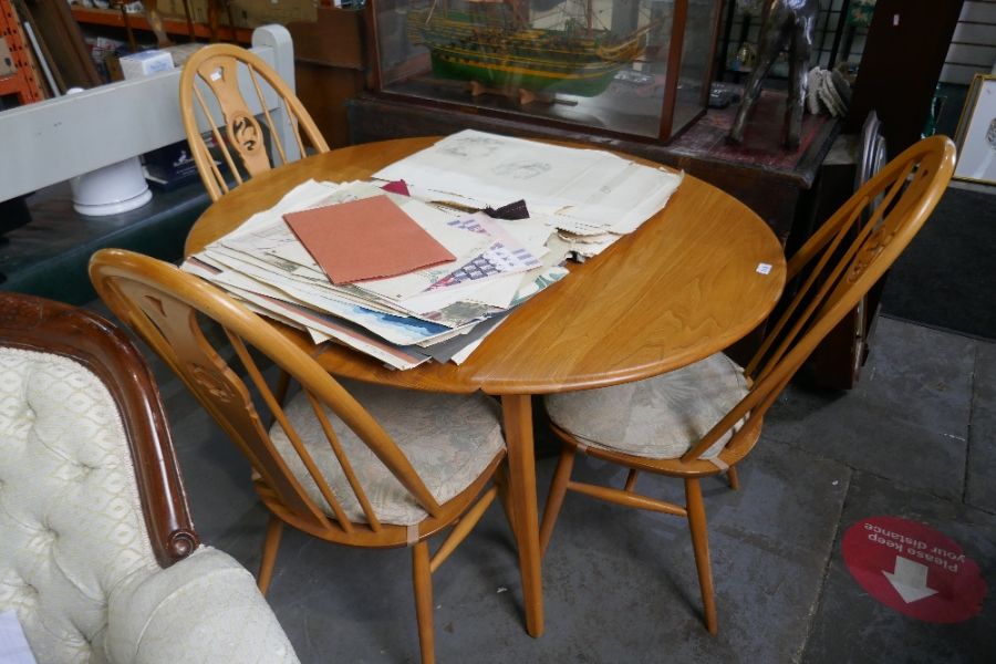 An Ercol elm two flap kitchen table on splay legs and a set of four stickback chairs with carved spl