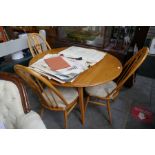 An Ercol elm two flap kitchen table on splay legs and a set of four stickback chairs with carved spl