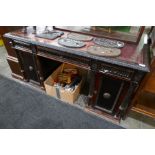 A late Victorian twin pedestal desk having cupboard doors with carved decoration, 143 cms