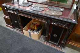 A late Victorian twin pedestal desk having cupboard doors with carved decoration, 143 cms
