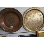 An Islamic brass circular tray with white metal lettering and one other copper example