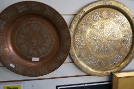 An Islamic brass circular tray with white metal lettering and one other copper example