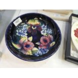 A blue ground Moorcroft bowl decorated with flowers and a boxed Moorcroft 1985 Year plate