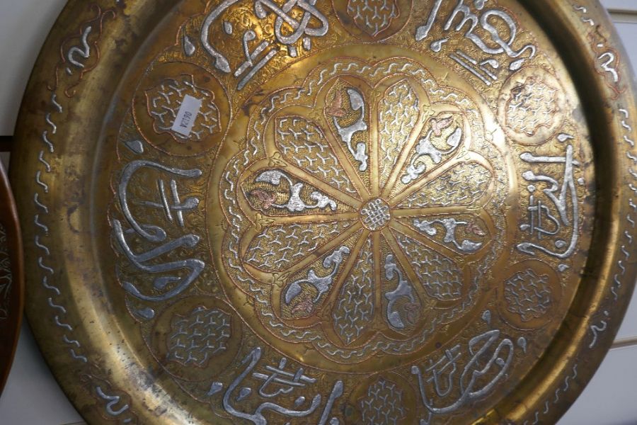 An Islamic brass circular tray with white metal lettering and one other copper example - Image 2 of 3