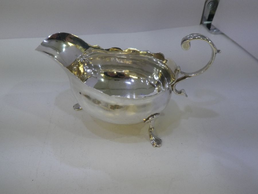 A Georgian silver sauceboat by Walter Brind, having a acanthus capped flying-scroll handle, scallope