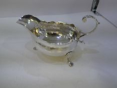 A Georgian silver sauceboat by Walter Brind, having a acanthus capped flying-scroll handle, scallope