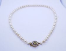 Vintage 9ct gold clasped single row pearl necklace, standard short, the clasp set with central perid