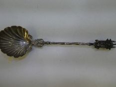 A white metal Church spoon having decorative scallop bowl and wrythen handle. With an ornate finial