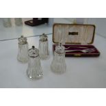 Two pairs of London 1915 salt and pepper sets having silver tops and very decorative cut glass bodie