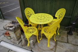 A cast aluminium garden table and chair set decorated in yellow