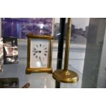 A brass carriage clock and an old brass adjustable magnifying glass