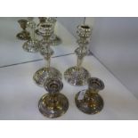 A pair of highly decorative silver candlesticks, heavily embossed in relief on a circular base with
