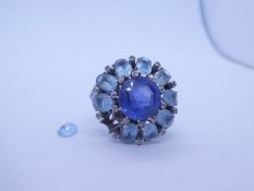 Unmarked white gold, possibly 14ct, cocktail ring with central blue round cut sapphire surrounded ov