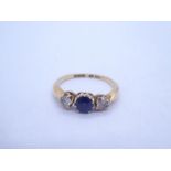 18ct yellow gold trilogy ring with central round cut sapphire flanked two clear stones, marked 18, s
