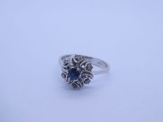 18K white gold dress ring with central round cut sapphire on a floral design mount inset small diamo