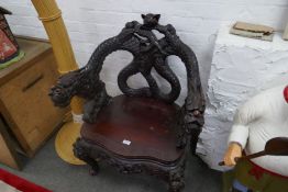 An oriental hardwood armchair having heavily carved decoration of dragons