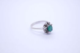 An 18ct white gold emerald and diamond cluster ring, with central oval cut emerald, surrounded 8 rou
