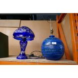 A modern bohemian blue glass lamp and one other globular ceramic lamp