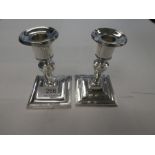 A pair of silver Victorian candlesticks on raised pedestal square bases. swag embossed detailing. Ha