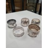 A quantity of five silver various napkin rings to include a pair. Some with ornate embossed design,