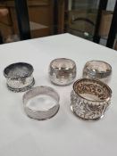 A quantity of five silver various napkin rings to include a pair. Some with ornate embossed design,