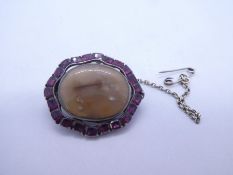Antique silver backed brooch with central oval agate panel, framed by 22 cushion cut rubies, with sa