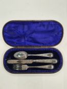A cased Christening set of a knife, fork and spoon. Heavily decorated with engraved foliate scrolls