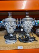 A pair of plated Victorian style urns decorated cherubs, converted to table lamps