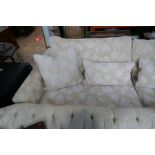 A large modern sofa having beige covers with white and brail decoration