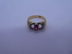 Yellow gold dress ring with central oval cut rubover set ruby flanked diamond set horseshoe shoulder