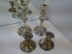 A pair of highly decorative silver candlesticks, heavily embossed in relief on a circular base with